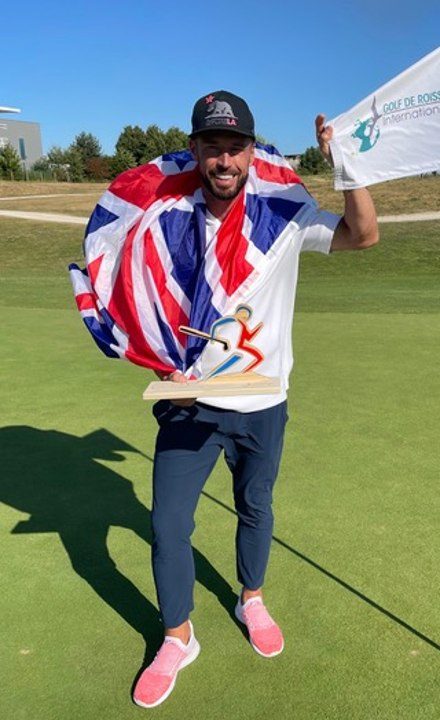 James Hardy holding the flag on the green, wrapped in a Union Jack