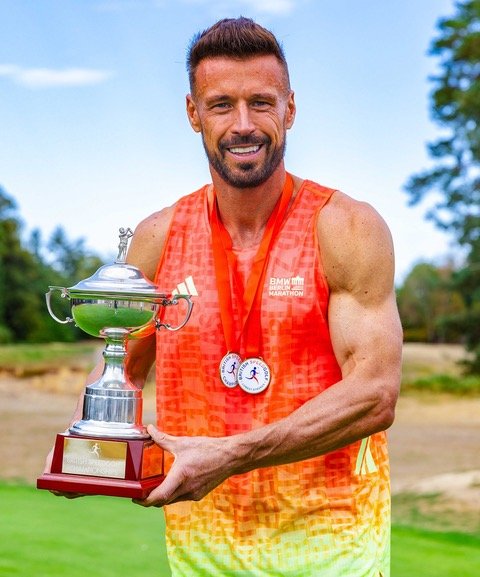 James Hardy holding the British Championship trophy, wearing his medals